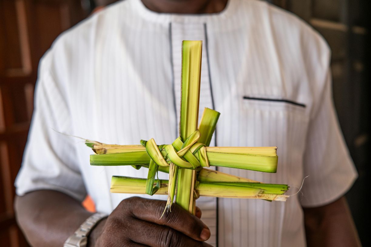 Hands holding a cross woven from palm fronds